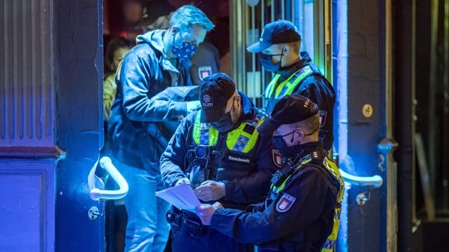 Polizisten kontrollieren in einer Kneipe die Einhaltung der Corona-Regeln: Die Party-Szene gilt als Ansteckungsherd. Polizisten kontrollieren in einer Kneipe die Einhaltung der Corona-Regeln: Die Party-Szene gilt als Ansteckungsherd.