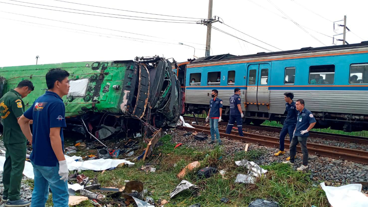 Rettungskräfte stehen an der Unfallstelle, wo Zug und Bus zusammenstießen: Der Bus stürzte bei dem Unglück um. Rettungskräfte stehen an der Unfallstelle, wo Zug und Bus zusammenstießen: Der Bus stürzte bei dem Unglück um.