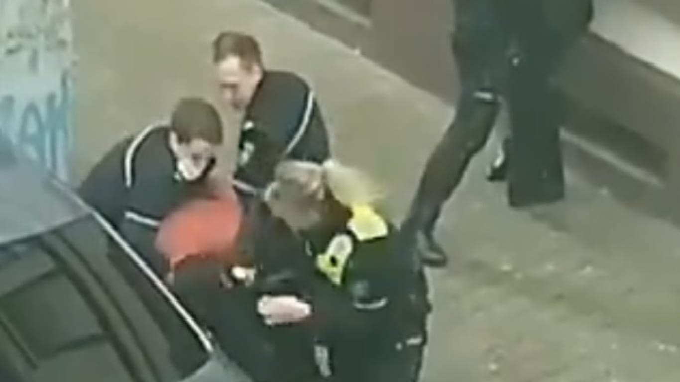Zwei Polizisten halten den Mann fest, während ihre Kollegin auf den Festgenommenen einboxt: Der Vorfall soll nun geprüft werden.