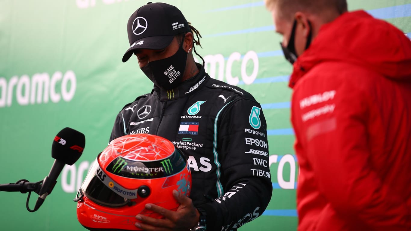 Sichtlich bewegt: Lewis Hamilton schaut auf den Helm, den ihm Mick Schumacher (r.) gerade überreicht hat.