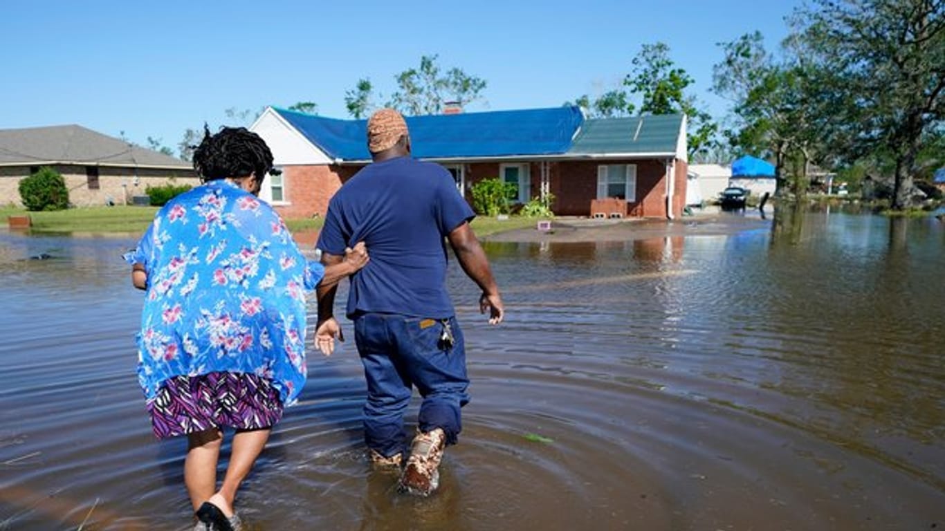 Zwei Menschen gehen durch eine überflutete Straße in Lake Charles (Louisiana).