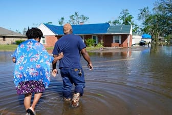 Zwei Menschen gehen durch eine überflutete Straße in Lake Charles (Louisiana).