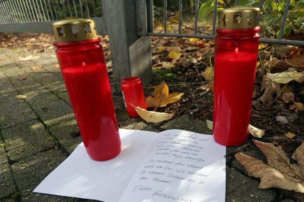 Kerzen und ein Brief liegen vor dem Gelände in Duisburg, auf dem ein Mädchen tot aufgefunden wurde.