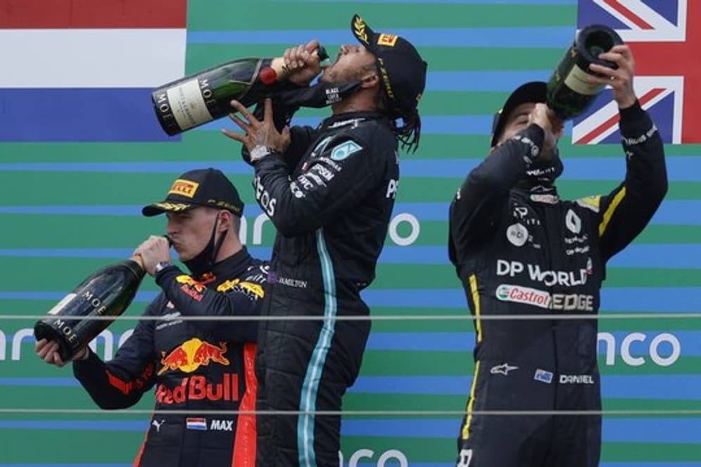 Auf dem Podest genehmigen sich der Zweitplatzierte Max Verstappen (l-r), Sieger Lewis Hamilton und Daniel Ricciardo zunächst einen großen Schluck.