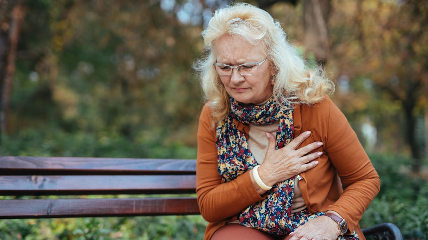 Frau hat Schmerzen und fasst sich an die Brust: Frauen sterben deutlich häufiger als Männer an einer Herzschwäche.