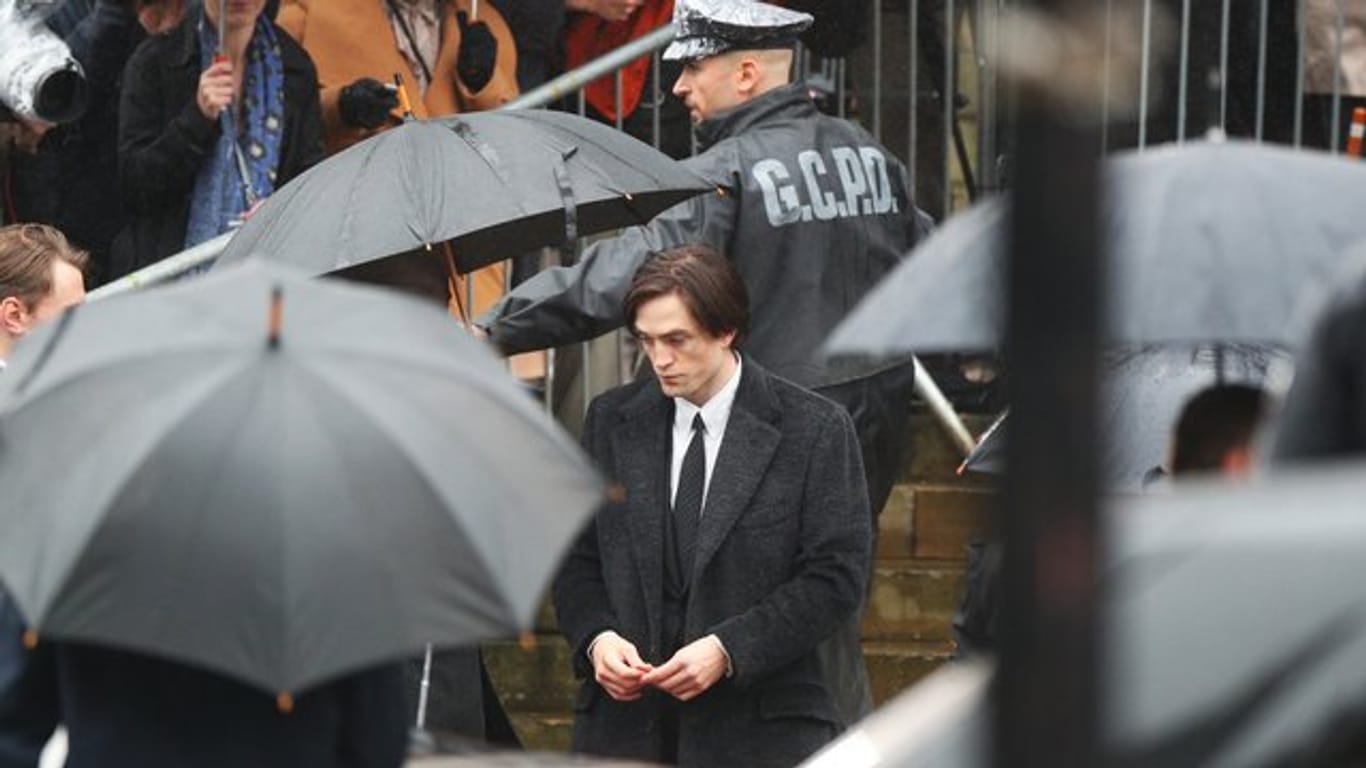 Robert Pattinson steht im Regen.