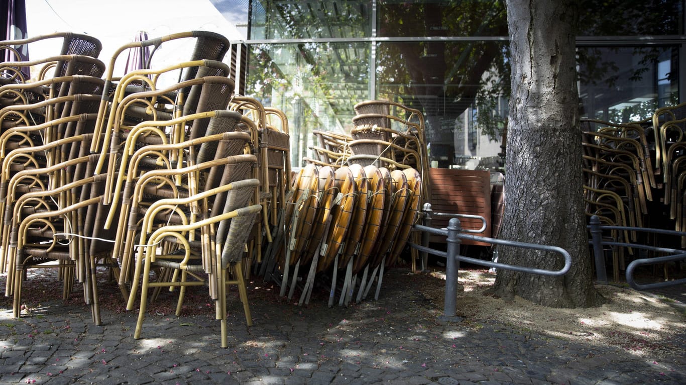 Gestapelte Stühle an einem Café am Münsterplatz in Bonn: Gasronomen sollen Pkw-Stellplätze den ganzen Winder über nutzen dürfen.