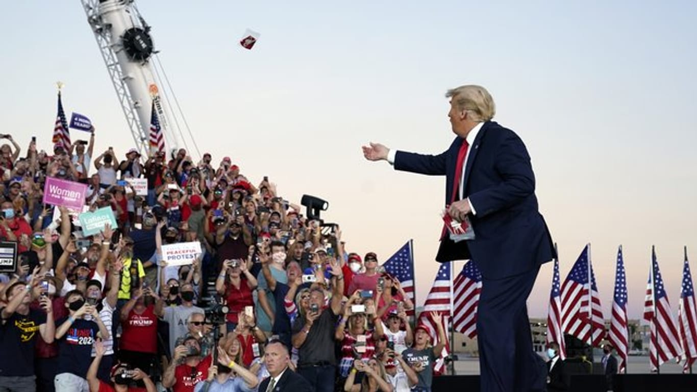 US-Präsident Trump wirft Gesichtsmasken in die Menge, als er zu einer Wahlkampfkundgebung am Orlando Sanford International Airport eintrifft.