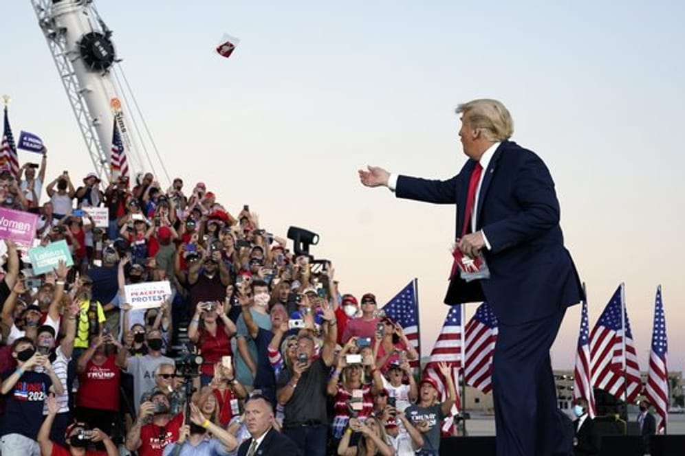 US-Präsident Trump wirft Gesichtsmasken in die Menge, als er zu einer Wahlkampfkundgebung am Orlando Sanford International Airport eintrifft.