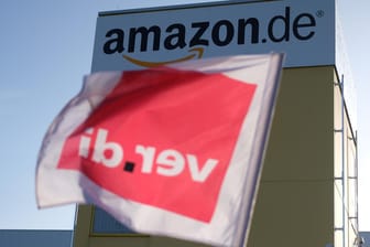 Eine Verdi-Fahne weht vor einem Amazon-Versandzentrum: Mit einem bundesweiten Streik will die Gewerkschaft für einen Tarifvertrag kämpfen.