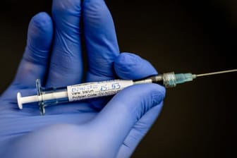 Ein Mann hält im Institut für Tropenmedizin an der Uniklinik Tübingen eine Spritze in der Hand, mit der einer jungen Frau, die erste Probandin, ein möglicher Wirkstoff gegen das Coronavirus gespritzt wurde.