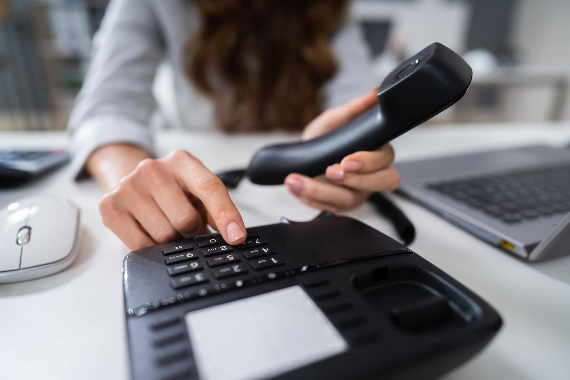 Eine Frau wählt am Telefon: Unternehmen setzen auf das Festnetztelefon.