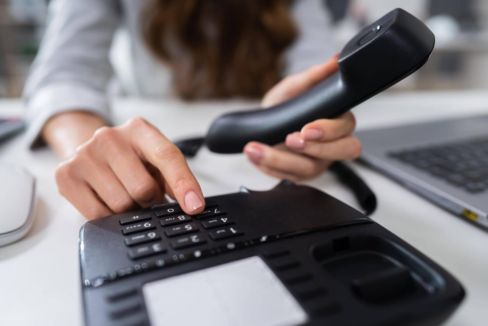 Eine Frau wählt am Telefon: Unternehmen setzen auf das Festnetztelefon.