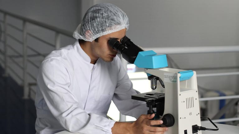 Mediziner am Mikroskop: Forscher haben die beiden Corona-Erkrankungen eines 25-Jährigen untersucht und genetische Unterschiede festgestellt.