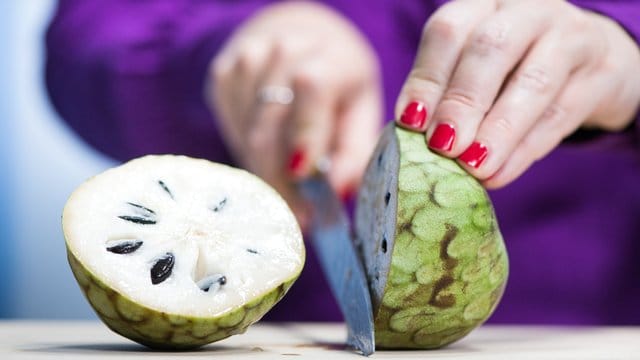 Die Cherimoya kann nach dem Halbieren wie eine Kiwi ausgelöffelt werden - aber ohne die Kerne, denn die sind nicht essbar.