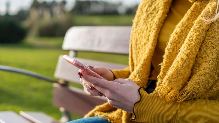 Eine Frau mit Smartphone in der Hand (Symbolbild): Android-Geräte können Sie auf verschiedene Weisen verschlüsseln.