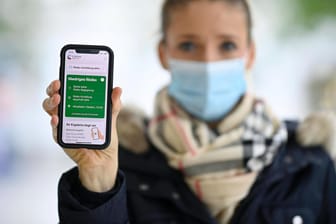 Eine junge Frau zeigt die Corona-Warn-App auf dem iPhone: Die Bundesregierung wirbt weiterhin für die App, die vor Risikokontakten warnen soll.