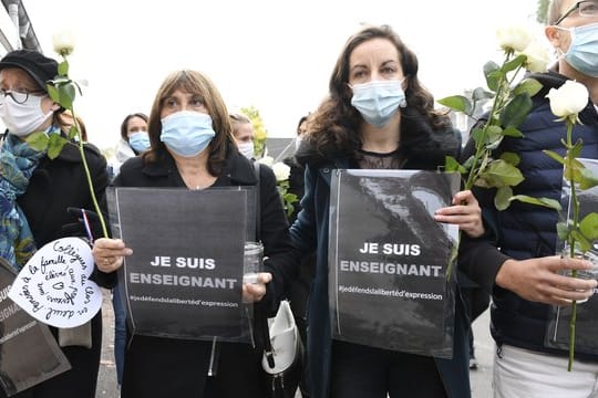 Mit Schildern mit Aufschriften wie "Ich bin Lehrer - Ich verteidige die Meinungsfreiheit" kommen Menschen in Conflans-Sainte-Honorine zum Gedenken zusammen.