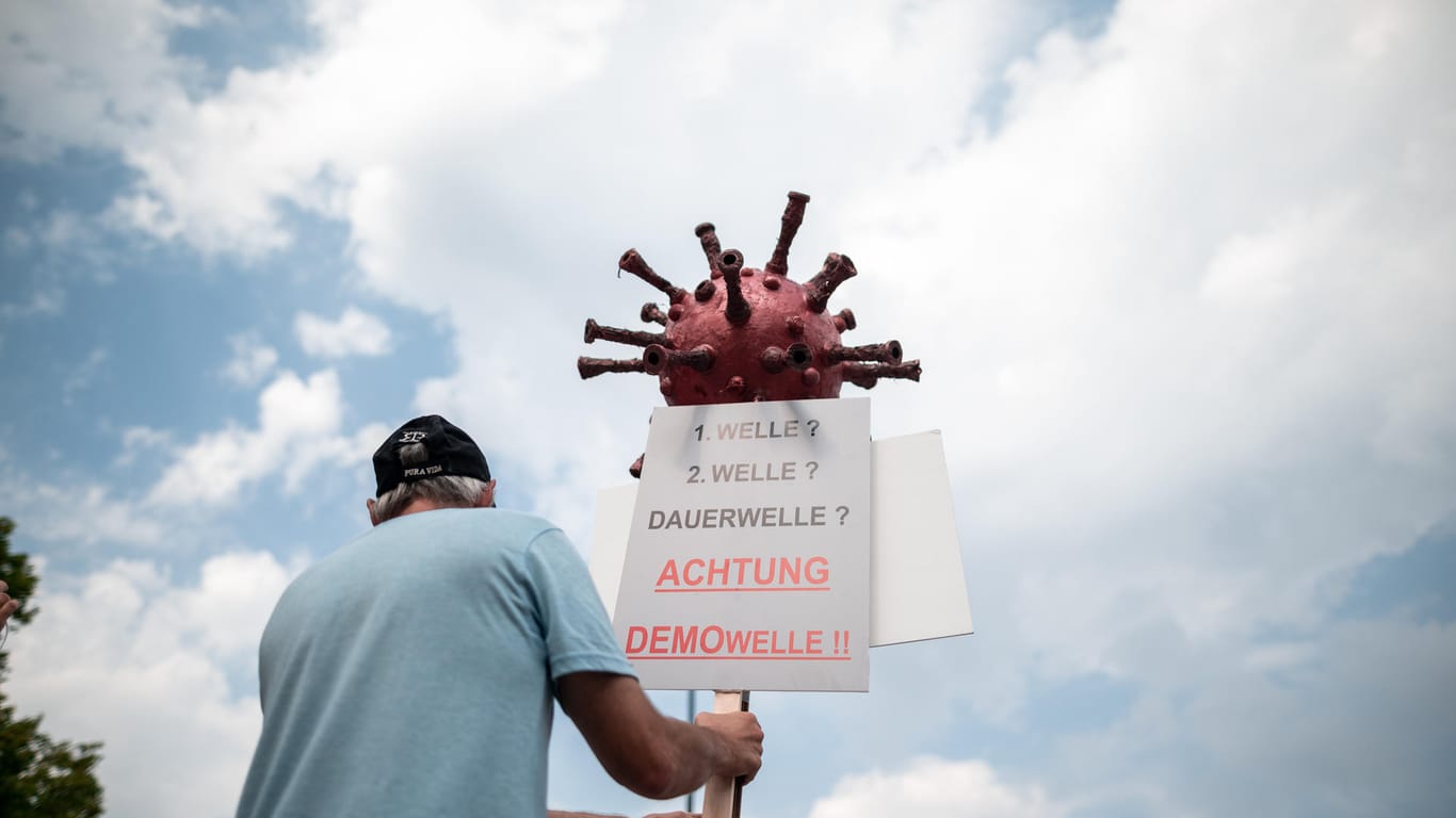 Ein Teilnehmer der Demonstration hält ein Schild mit der Aufschrift "1.Welle, 2. Welle, Dauerwelle, Achtung Demowelle" in die Luft: In Dortmund wurde gegen die Corona-Maßnahmen demonstriert.