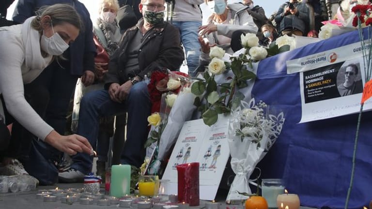 Eine Frau zündet eine Kerze an: Zahlreiche Menschen haben sich nach der brutalen Ermordung eines Lehrers am Wochenende zu einer Solidaritätsdemonstration in Paris versammelt.