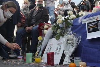 Eine Frau zündet eine Kerze an: Zahlreiche Menschen haben sich nach der brutalen Ermordung eines Lehrers am Wochenende zu einer Solidaritätsdemonstration in Paris versammelt.