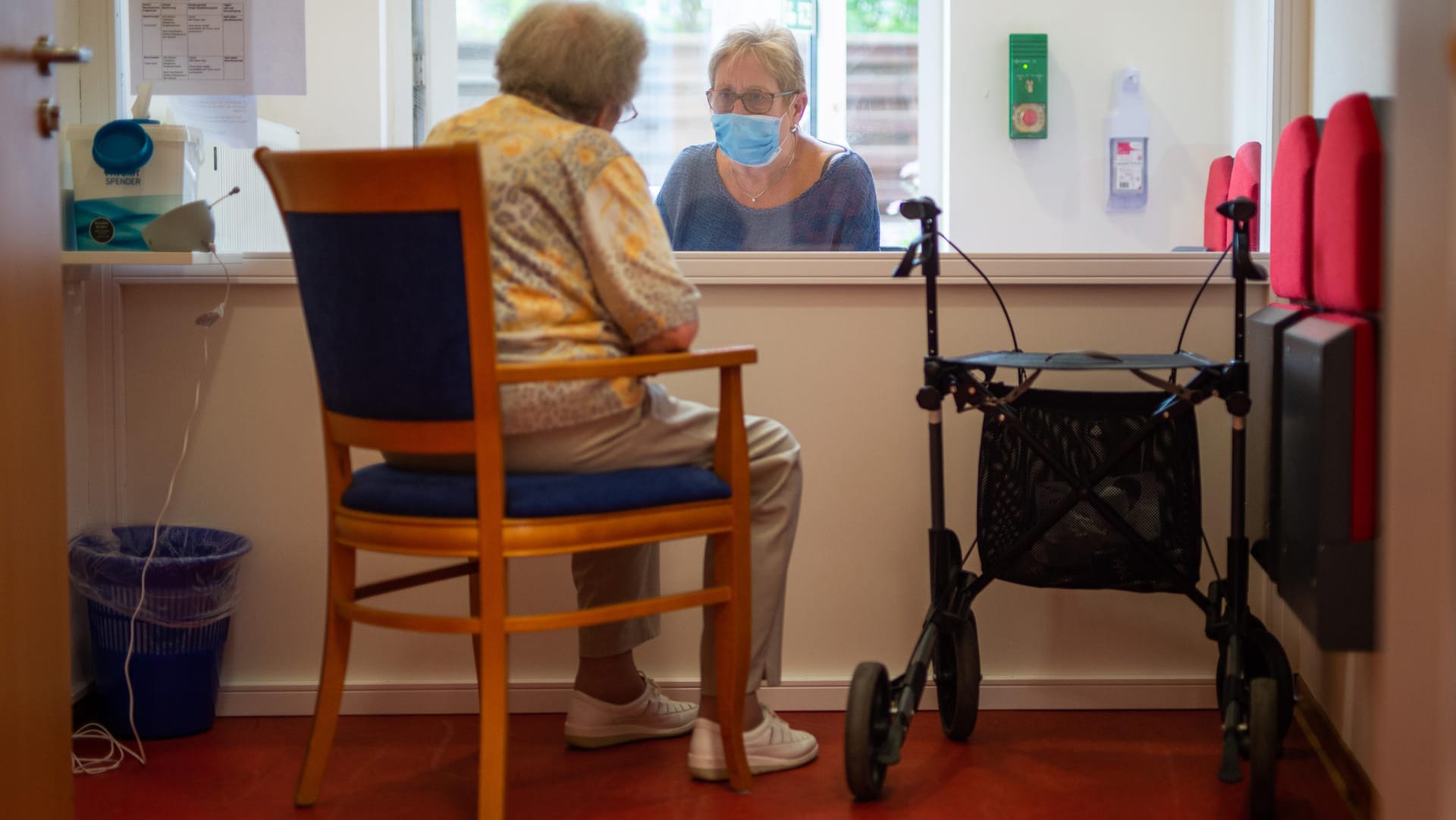 Solingen: Eine Besucherin unterhält sich im Besuchsraum eines Alteheimes mit ihrer Angehörigen. Dabei werden sie von einer Scheibe getrennt.