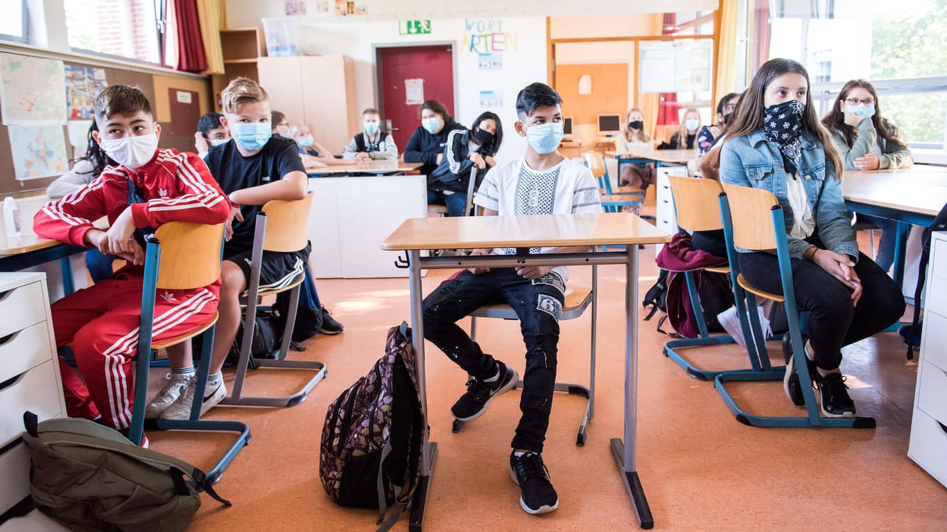 Hamburg: Schüler einer 7. Klasse der Max-Schmeling-Stadtteilschule sitzen zu Beginn des Unterrichts mit Mund-Nasen-Bedeckungen im Klassenraum.
