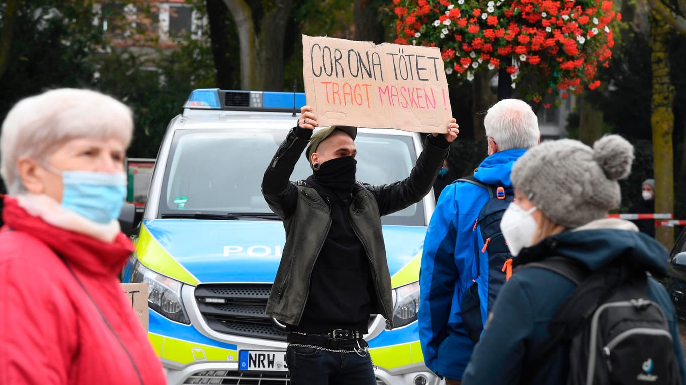 Ein Gegendemonstrant mit einem Schild: "Corona tötet. Tragt Masken!"