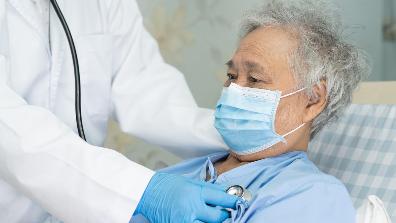 Patient mit Mund-Nasen-Schutz wird von Arzt untersucht: Für Patienten mit Herzschwäche kann das Tragen einer Alltagsmaske lebensrettend sein