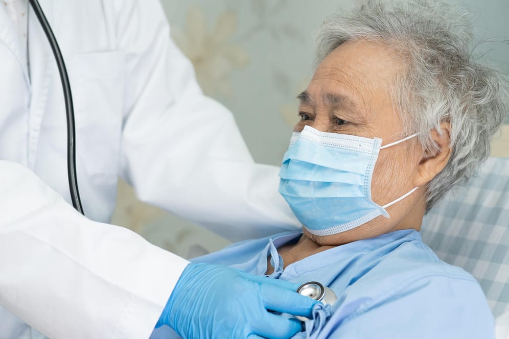 Patient mit Mund-Nasen-Schutz wird von Arzt untersucht: Für Patienten mit Herzschwäche kann das Tragen einer Alltagsmaske lebensrettend sein