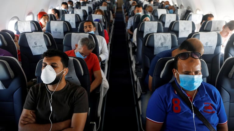 Maskenpflicht zum Schutz vor einer Corona-Infektion: Passagiere sitzen mit Mund-Nasen-Schutz im Flugzeug.
