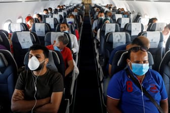 Maskenpflicht zum Schutz vor einer Corona-Infektion: Passagiere sitzen mit Mund-Nasen-Schutz im Flugzeug.