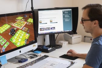 Maximilian Metzler, Mitarbeiter des Spiele Verlages Merz, spielt am Computer das Spiel "My Farm Shop".