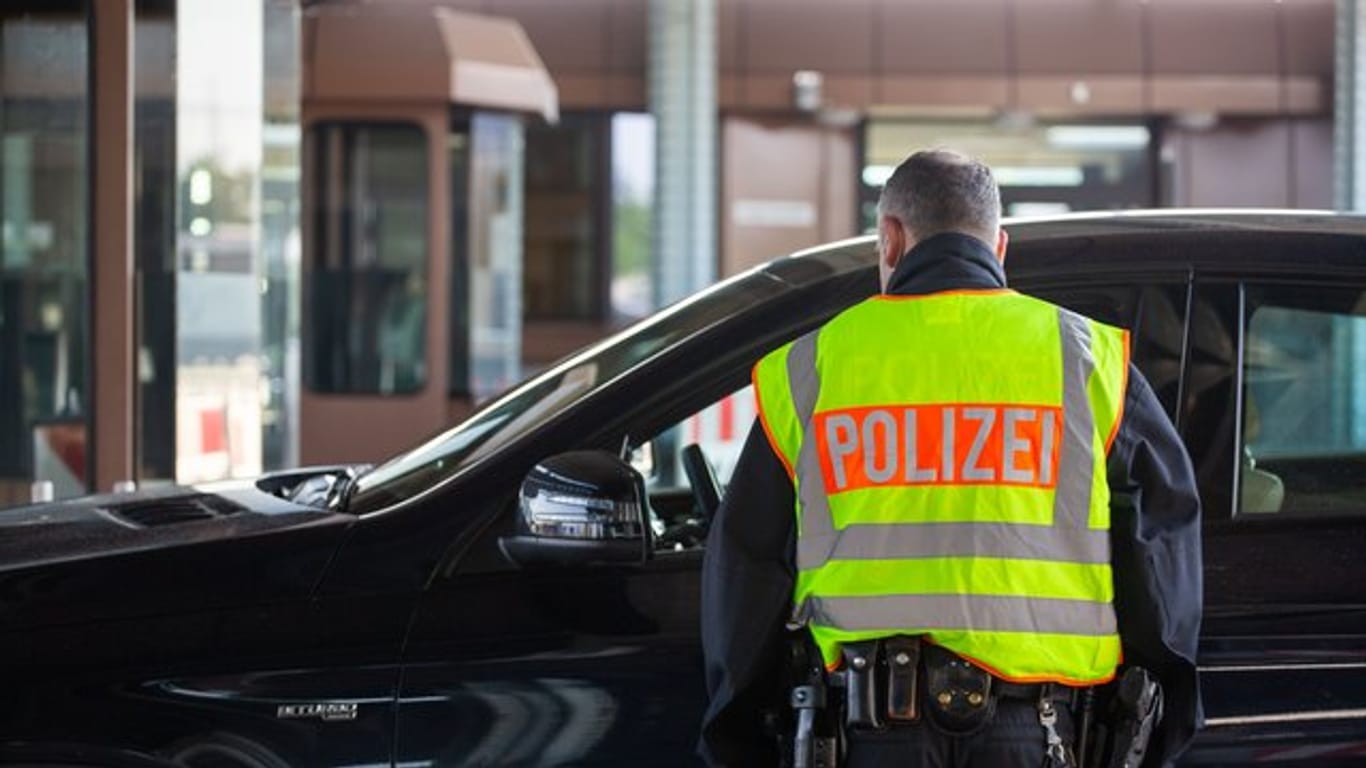 Ein Beamter der Bundespolizei kontrolliert an einem Grenzübergang einen Autofahrer.