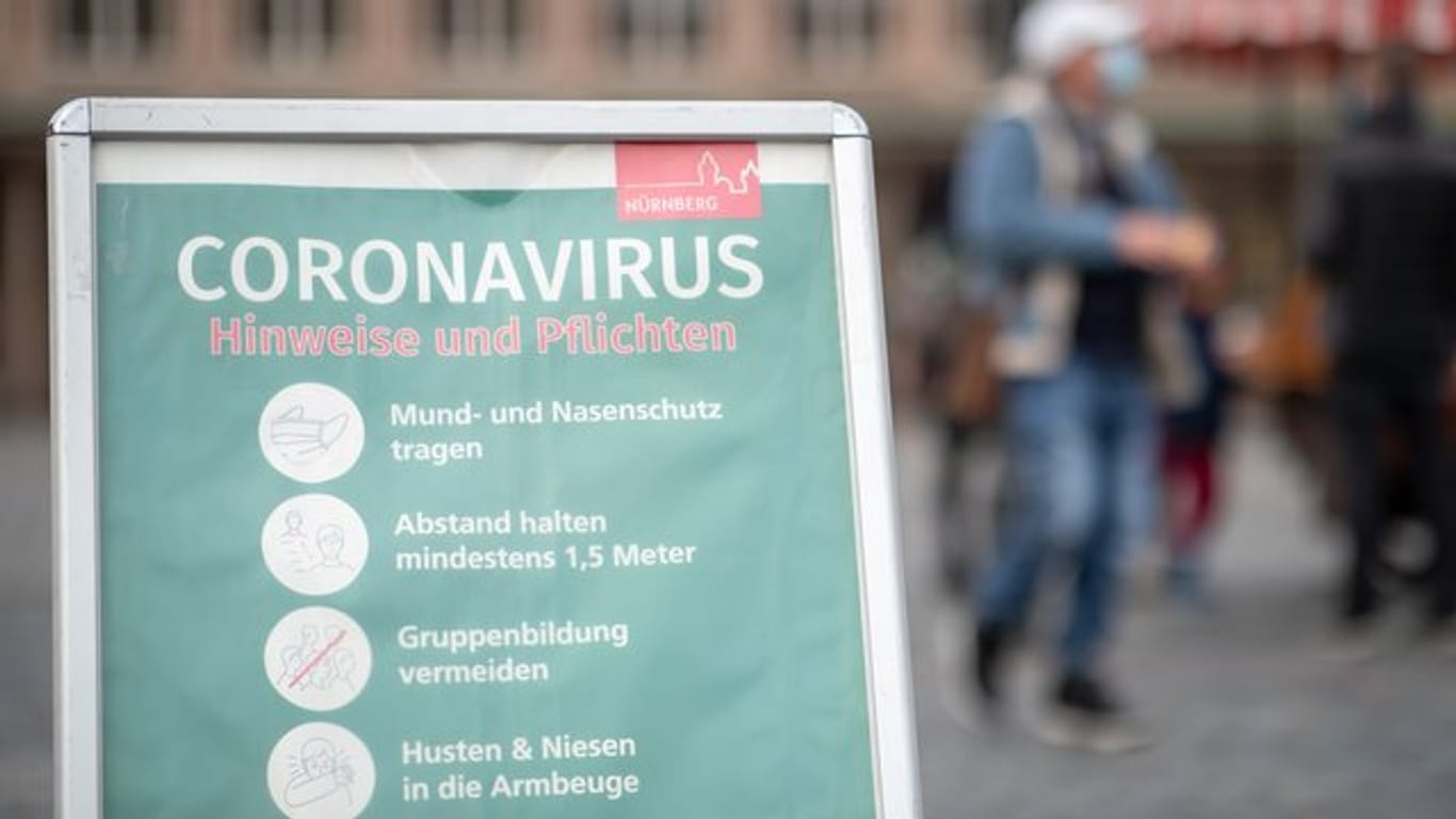 Ein Schild informiert Passanten auf dem Nürnberger Hauptmarkt über die Maskenpflicht und weitere Regeln.
