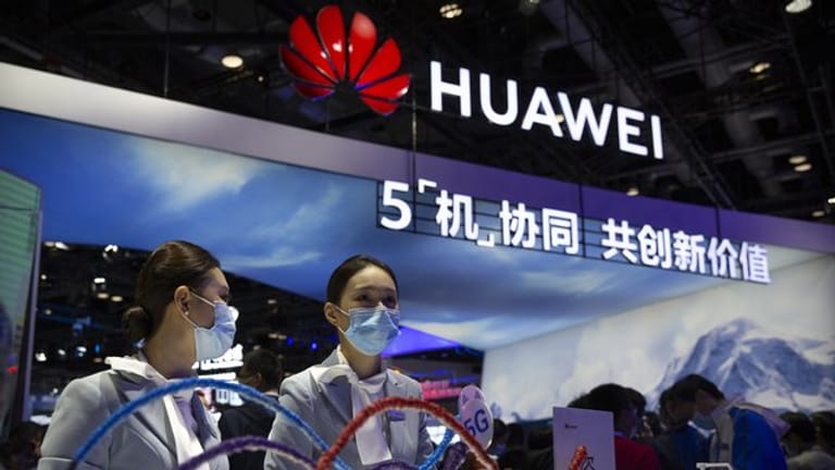 Mitarbeiter stehen an einem Stand des chinesischen Technologieunternehmens Huawei auf der PT Expo in Peking.
