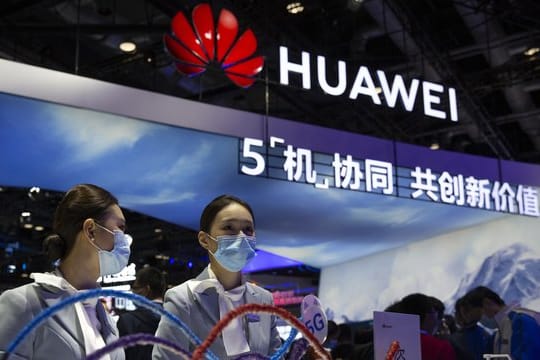 Mitarbeiter stehen an einem Stand des chinesischen Technologieunternehmens Huawei auf der PT Expo in Peking.