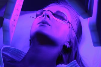 Eine junge Frau bei einer Lichttherapie: Blaues Licht soll sich positiv auf die Hautstruktur auswirken. Doch Experten streiten über die Wirksamkeit.
