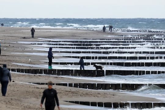 Spaziergänger sind am Strand bei Graal-Müritz unterwegs.