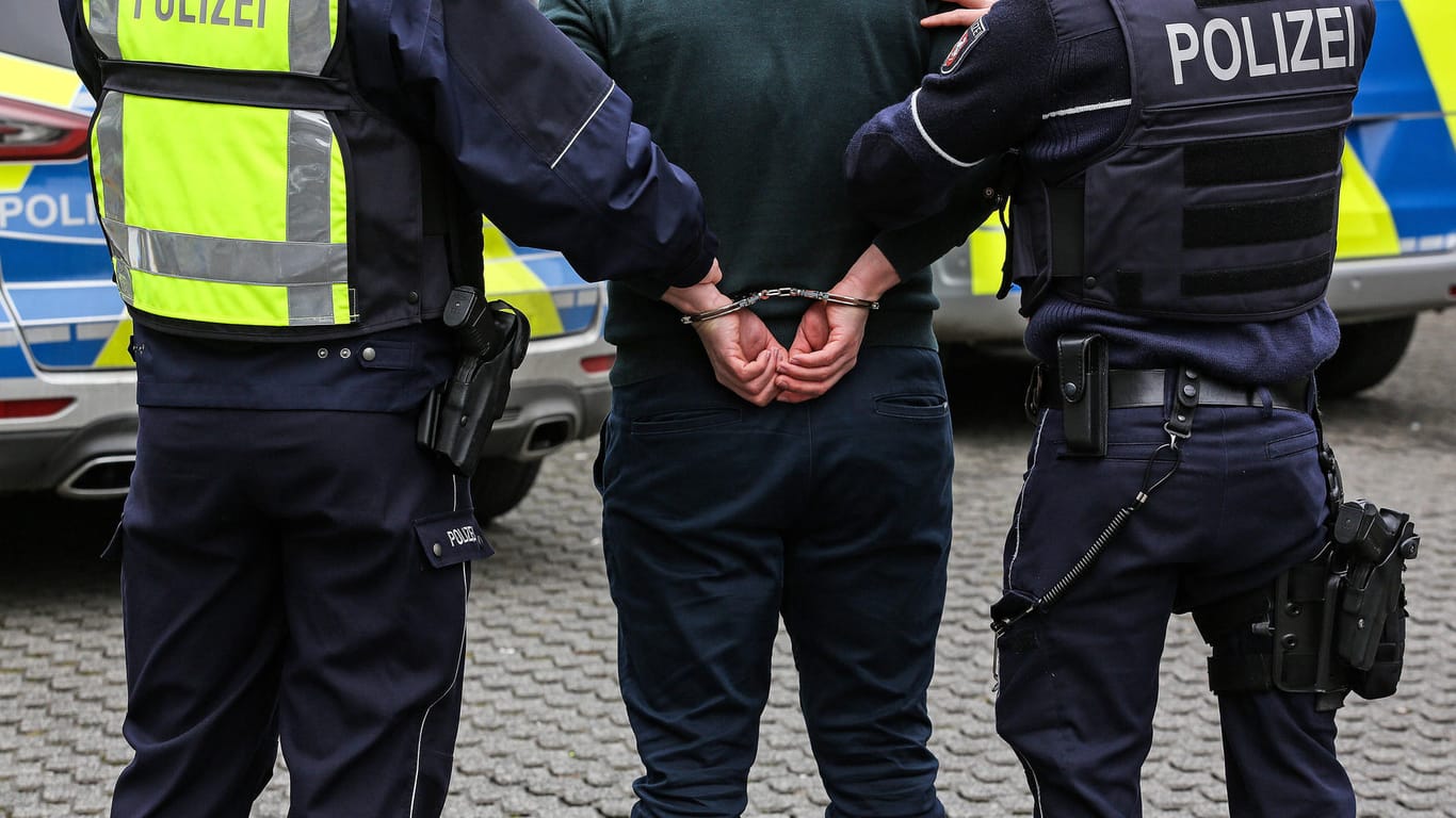 Zwei Polizisten führen einen Mann in Handschellen ab (Symbolbild): Auch ein alkoholisierter Hagener konnte nur mithilfe von Handschellen gebändigt werden.