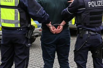 Zwei Polizisten führen einen Mann in Handschellen ab (Symbolbild): Auch ein alkoholisierter Hagener konnte nur mithilfe von Handschellen gebändigt werden.