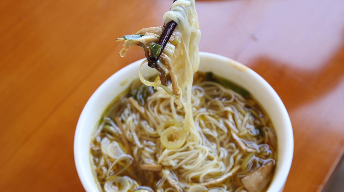 Nudeln einer chinesischen Suppe werden auf Stäbchen gehalten (Symbolbild): In China sind neun Menschen nach dem Verzehr von fermentierten Nudeln gestorben.