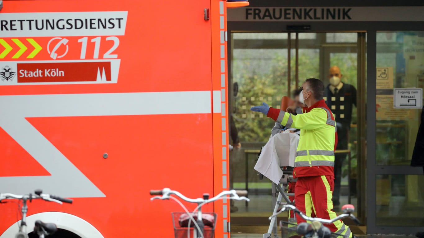 Ein Rettungssanitäter bringt vor der Frauenklinik eine Patientin zu einem Krankenwagen: In der Nähe der Universitätsklinik in Köln muss eine Weltkriegsbombe entschärft werden.