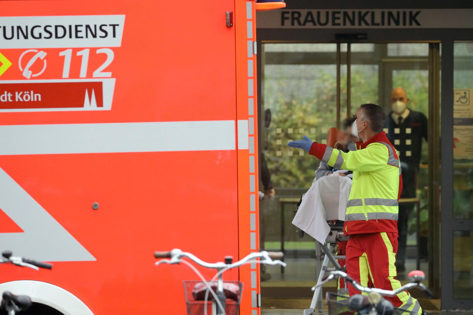 Ein Rettungssanitäter bringt vor der Frauenklinik eine Patientin zu einem Krankenwagen: In der Nähe der Universitätsklinik in Köln muss eine Weltkriegsbombe entschärft werden.