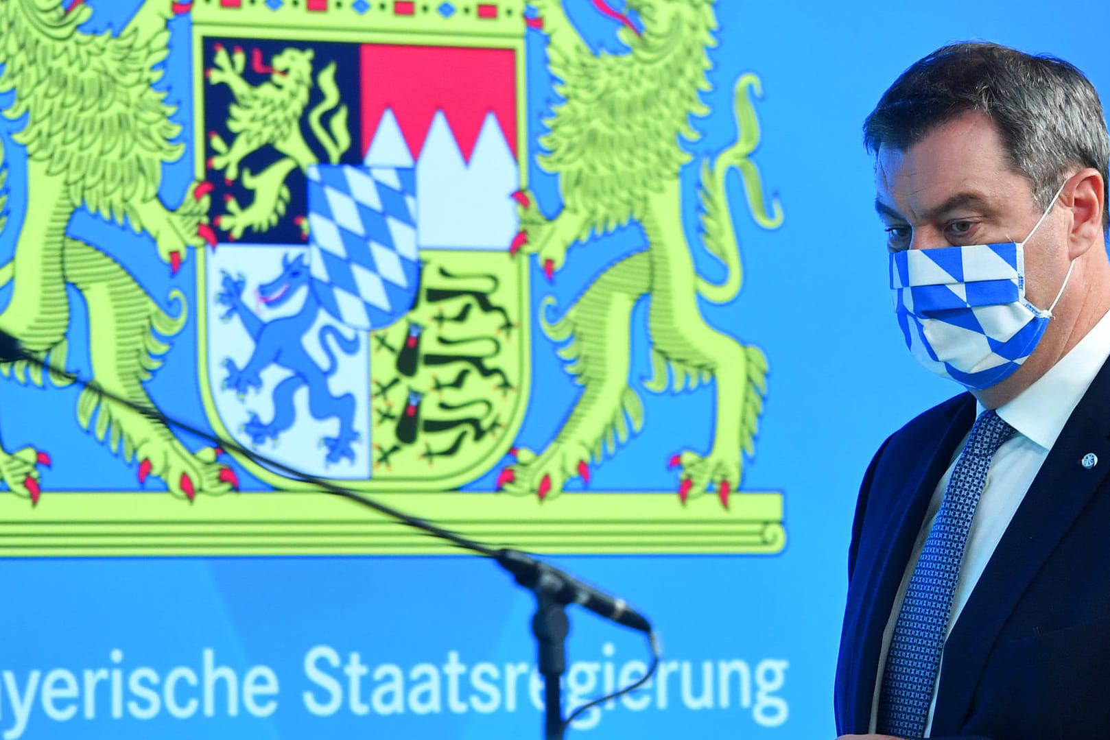 Bayerns Ministerpräsident Söder mit Mundschutz vor bayerischem Wappen: Söder kündigt eine neue Warnstufe an.