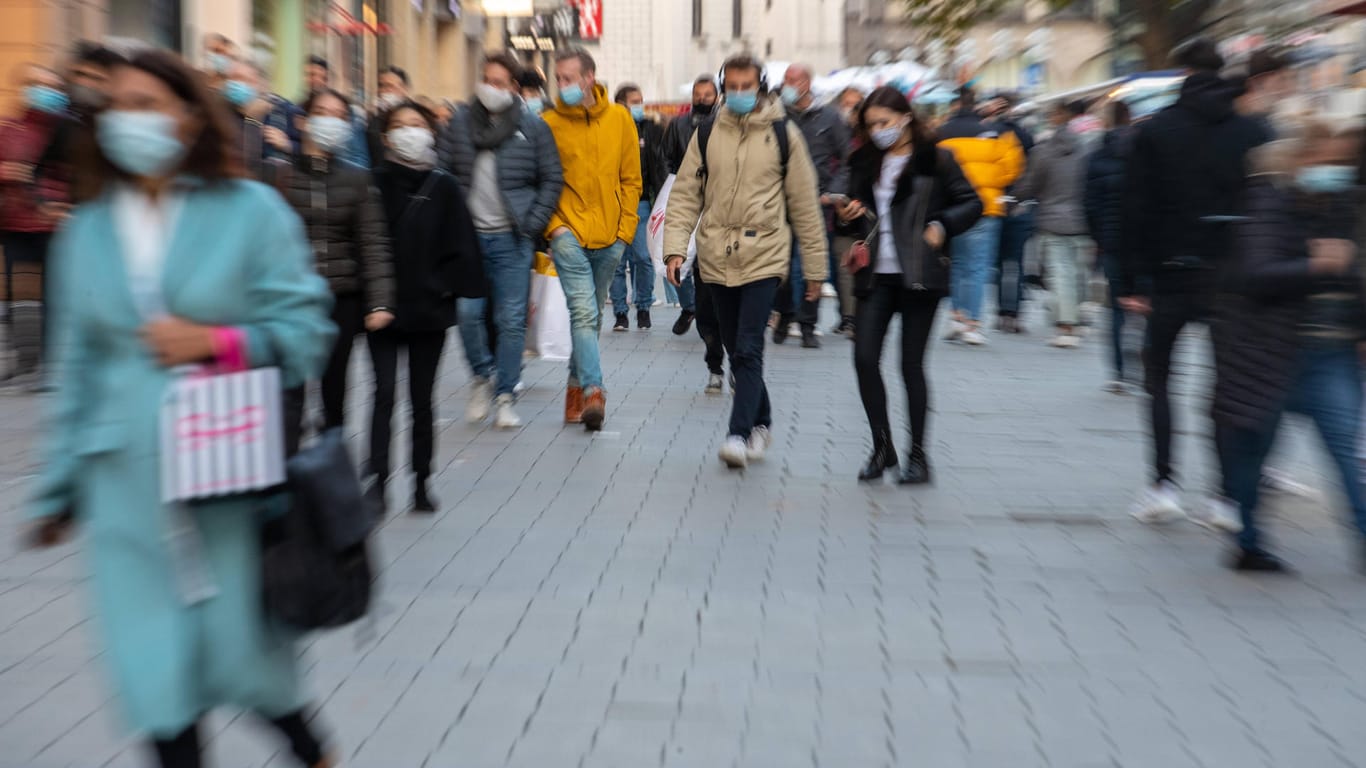 Menschen mit Masken in einer Einkaufsstraße (Symbolbild): In Bonn halten sich die Menschen weitestgehend an die Regel.