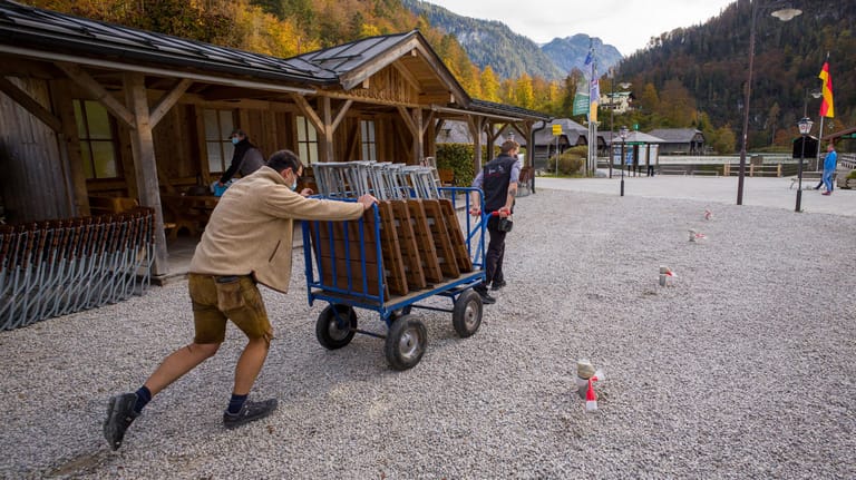 Zwei Mitarbeiter räumen am Königssee einen Biergarten leer: Im Landkreis Berchtesgadener Land gelten strenge Corona-Auflagen.