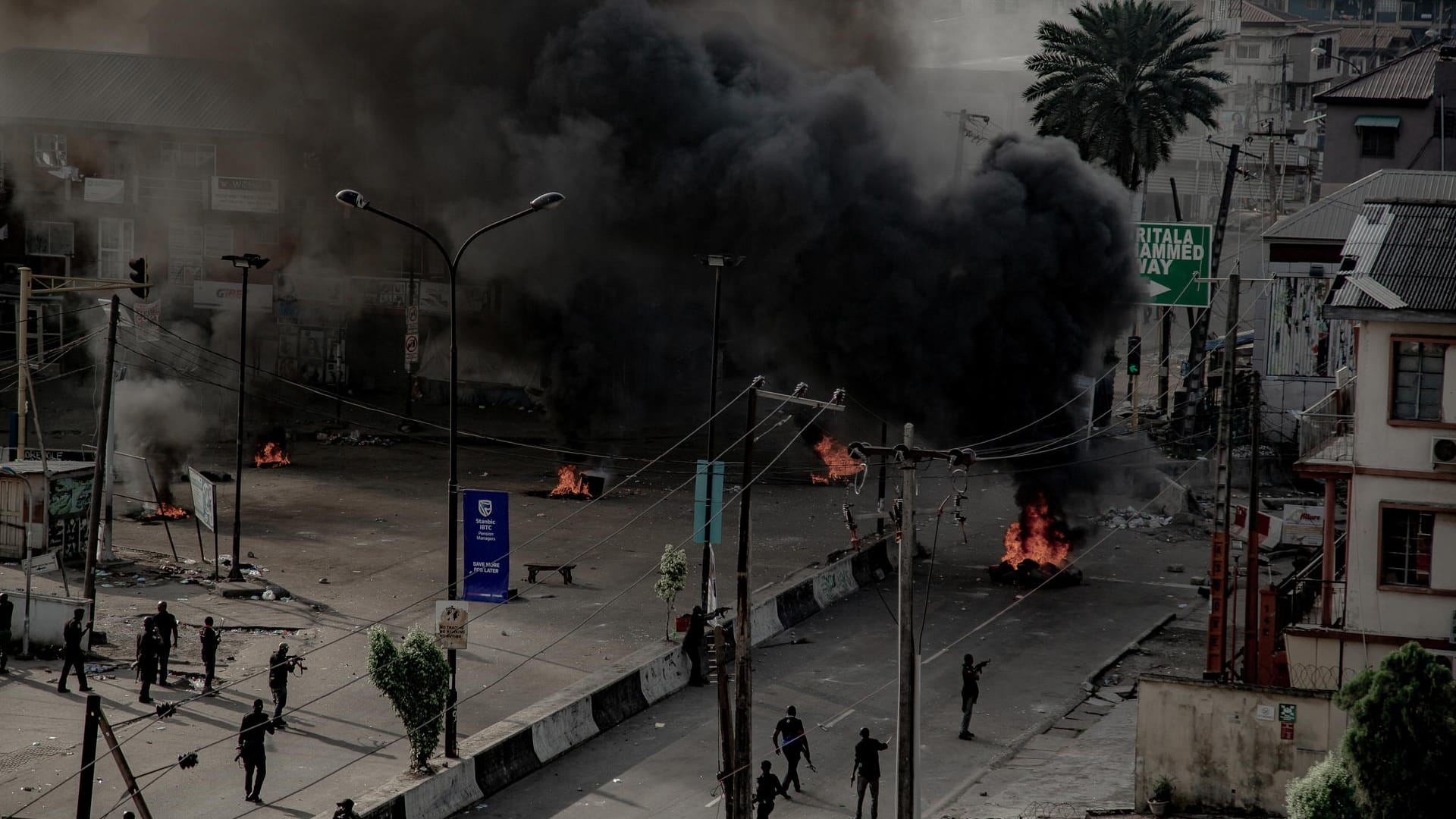 Männer mit Waffen patrouillieren brennende Straßen. in Lagos: Trotz einer Ausgangsperre bleibt die Lage in Nigerias Metropole weiter unübersichtlich.