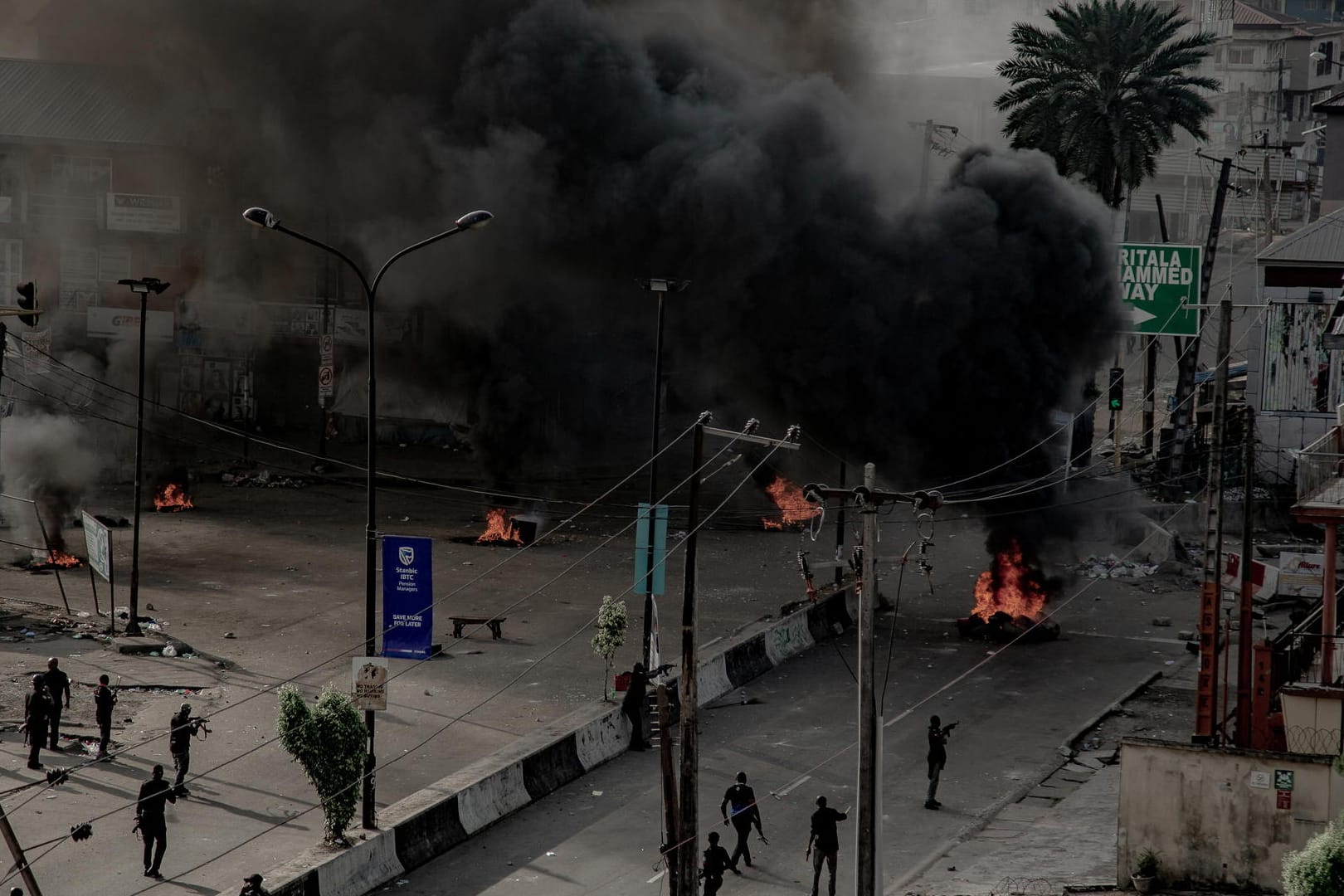 Männer mit Waffen patrouillieren brennende Straßen. in Lagos: Trotz einer Ausgangsperre bleibt die Lage in Nigerias Metropole weiter unübersichtlich.