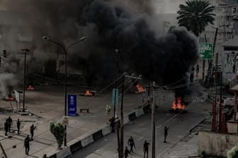 Männer mit Waffen patrouillieren brennende Straßen. in Lagos: Trotz einer Ausgangsperre bleibt die Lage in Nigerias Metropole weiter unübersichtlich.